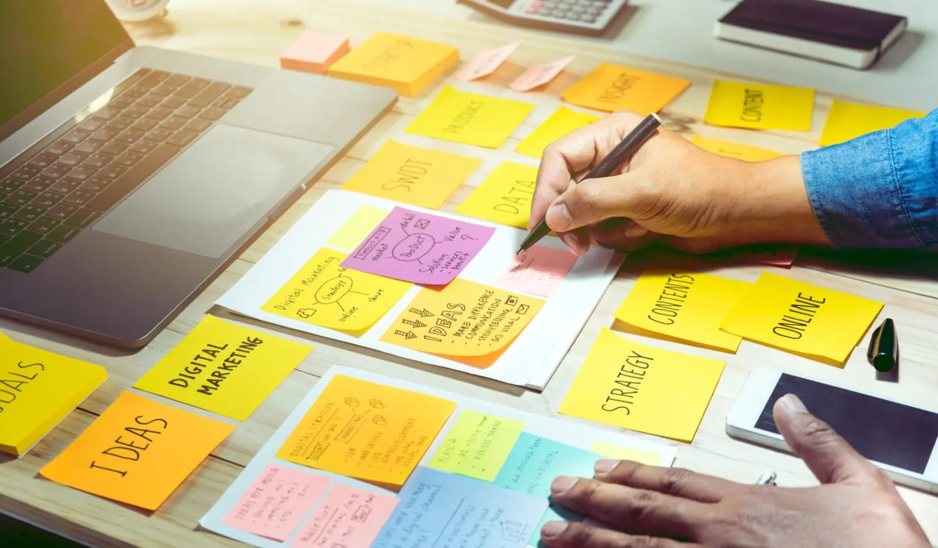 GettyImages-700980994 A person writing on post it notes with a pen.